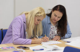 Zwei Frauen sitzen an einem Tisch und schreiben konzentriert.