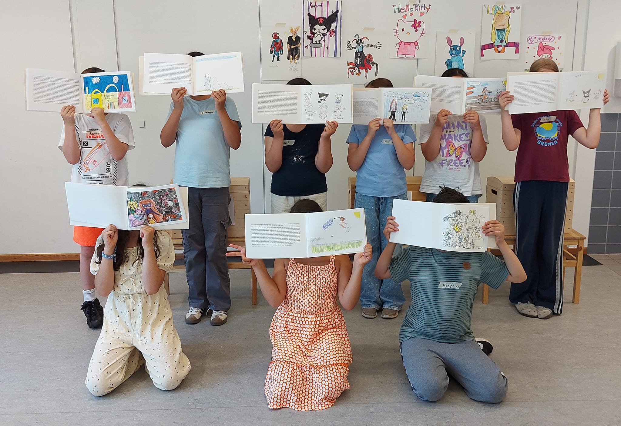 Eine Gruppe von Kindern. Jedes Kind hält sein selbst gestaltetes Buch vor das Gesicht.