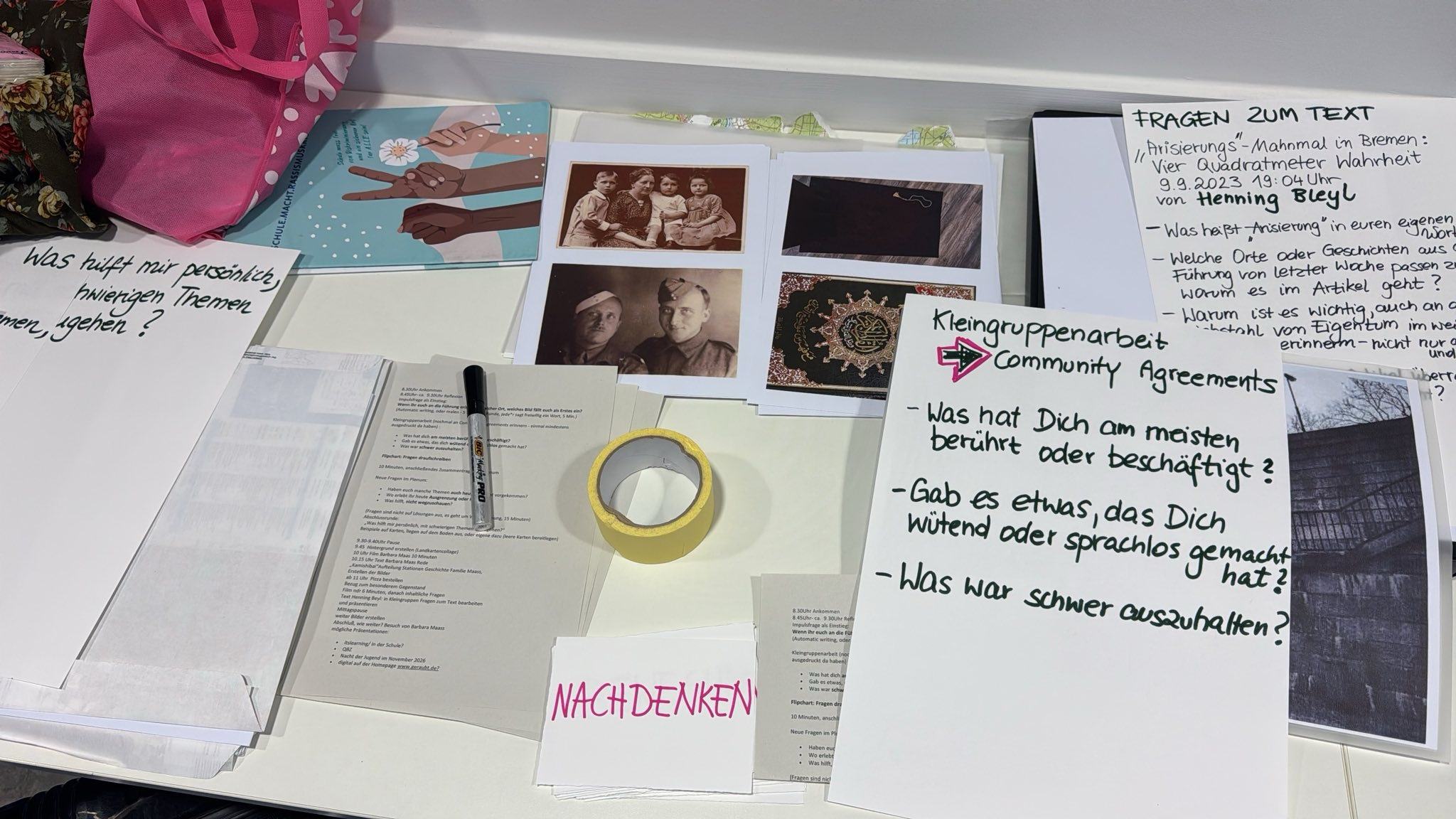 Auf einem Tisch liegen alte Fotos, Notizen, Stift und Klebeband, die den Erarbeitungsprozess zeigen.