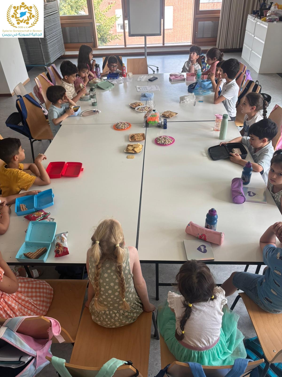 Kinder, die am Arabisch-Unterricht der Syrischen Gemeinschaft Bremen teilnehmen, sitzen um einen großen Tisch