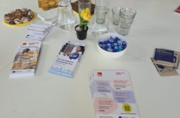 Auf einem weißen Tische liegen Info-Flyer und Knabbereien