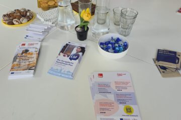 Auf einem weißen Tische liegen Info-Flyer und Knabbereien